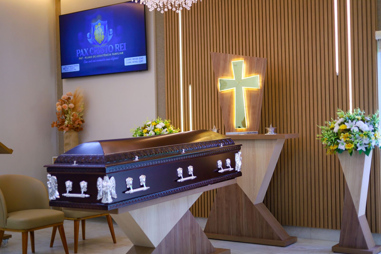 Altar da capela, com cruz iluminada e arranjos de flores